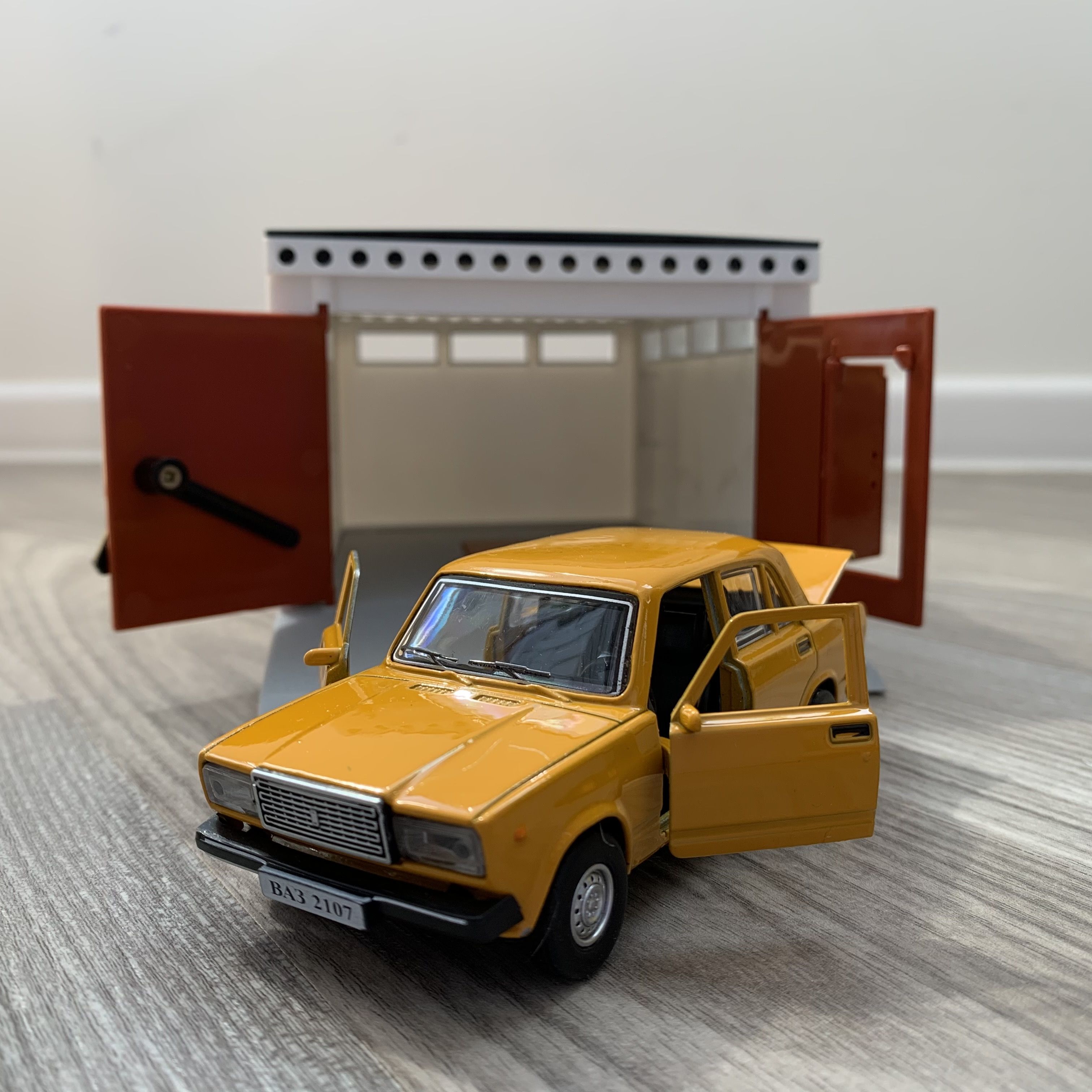 Гараж с распашными воротами и металлическая машинка 12 см модель ВАЗ 2107 инерция, 2 откр. двери и багажник - оранжевая